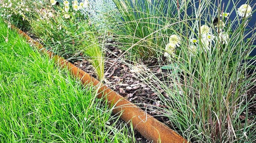 Cortenový obrubník oddeľujúci trávnik od záhonu s trávami